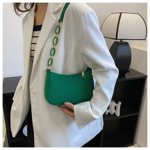Close-up of green crocodile pattern felt baguette bag with plastic chain strap on model