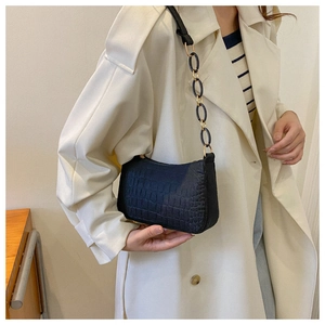 Detail of crocodile embossed black baguette bag with gold metal and acrylic chain strap