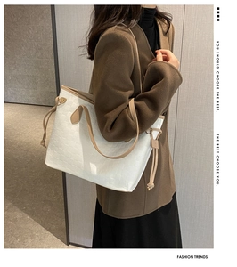 Detail of large tote bag with white weave texture and brown leather handles on model