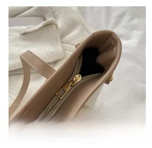 Detail of smooth gold metal zipper on beige leather tote bag for women