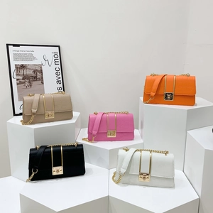 Fünf Crossbody-Taschen mit Krokoprägung in verschiedenen Farben auf weißen Podesten