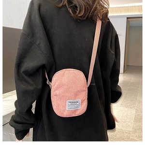 Pink corduroy mini crossbody bag shown on a model in a stylish indoor setting