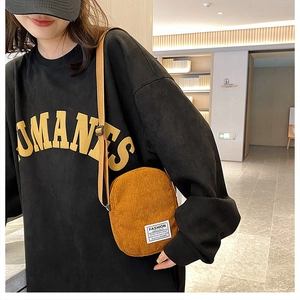 Detailed shot of ginger corduroy mini crossbody bag worn with a black oversized tee
