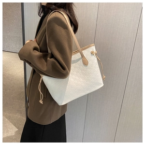 Detailed side view of white woven tote bag with brown straps worn on a chic wool coat