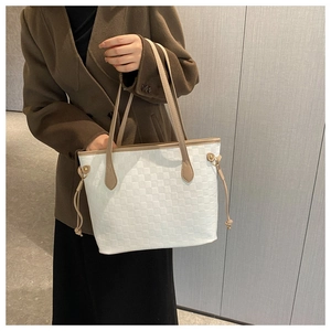 Detail of white quilted tote bag with khaki leather handles and woven checkerboard texture
