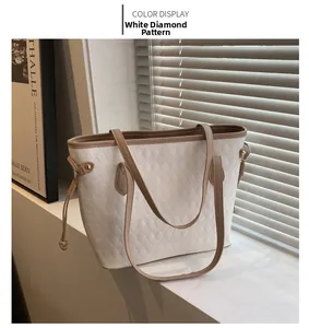 Close-up of white quilted tote bag with brown leather trim and drawstring side detail