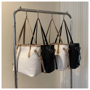 Detailed close-up of quilted tote bags in white and black with drawstring and gold hardware