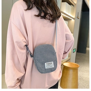 Close-up of grey corduroy crossbody bag with Fashion Instinct label worn by model