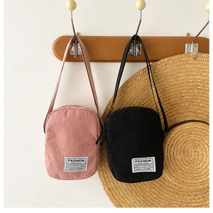 Detail of pink and black corduroy crossbody bags with white decorative fabric labels
