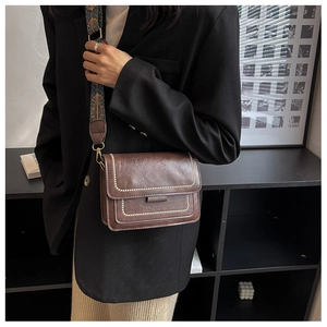 Close-up of vintage brown crossbody bag with gold studs and embroidered wide strap