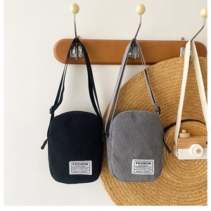 Detail of corduroy crossbody bags in black and gray with textured vertical stripes