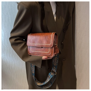 Close-up of vintage brown leather square bag with patterned wide shoulder strap