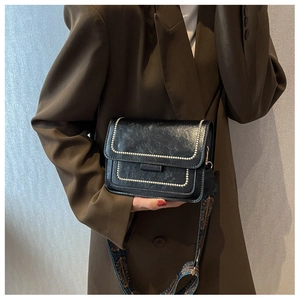 Detail of vintage black square bag with pearl edges and patterned wide shoulder strap