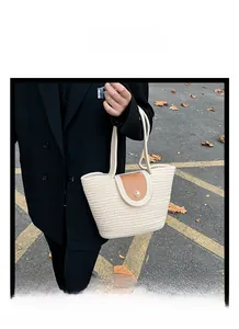 Detail of woven straw tote bag with pearl buckle and brown leather flap on street