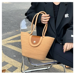 Detail of woven straw tote bag with brown leather flap and large pearl button closure