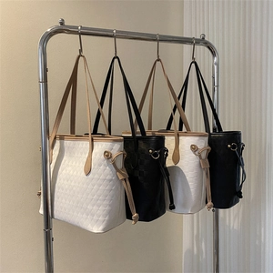 Quilted tote bags set in black and white with leather handles on a display stand