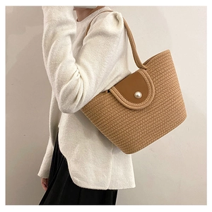 Close-up of woven straw tote bag featuring a leather flap and elegant pearl closure