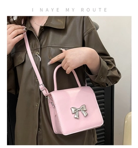 Detailed view of pink crossbody bag with silver bow ornament and adjustable strap