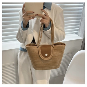 Detailed close-up of the woven texture and pearl closure on a khaki tote bucket bag
