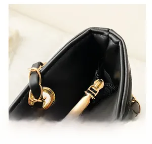 Detail of black quilted leather bag with gold metal zipper and chain strap