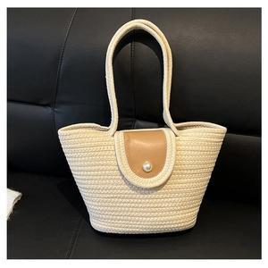 Detail of woven straw bucket bag with brown leather flap and large pearl buckle closure