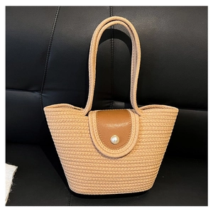 Detail of woven straw tote bag with brown leather flap and pearl button closure
