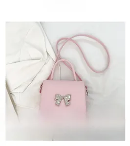 Detailed view of pink leather crossbody bag with silver bow accent on white blazer