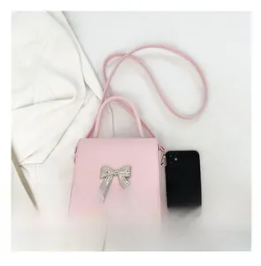 Pink mini square bag with silver bow detail and smartphone for size comparison