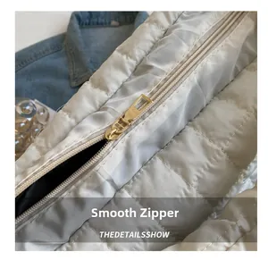 Detail of smooth gold zipper and white quilted padded fabric on oversized crossbody bag