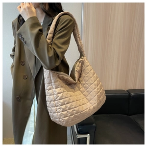 Detailed view of beige quilted tote bag showing padded strap and silky fabric texture