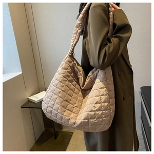 Detailed view of champagne quilted nylon tote bag worn with a brown coat for winter