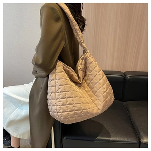 Close-up of beige quilted tote bag with large capacity and soft padded fabric details