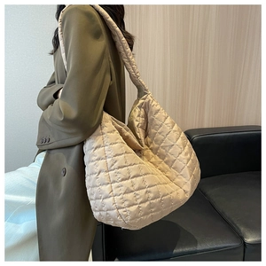 Quilted tote bag in champagne gold shown on shoulder over an olive coat