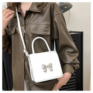 Mini white leather crossbody bag with silver metal bow accent and top handle style