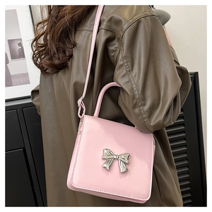 Pink square shoulder bag with silver metallic bow on a brown leather jacket