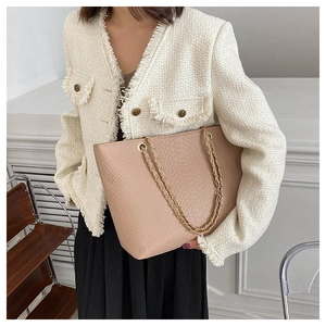 Detailed view of pink snakeskin pattern tote bag with golden chain strap on a model