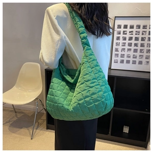 Puffy green quilted tote bag made of nylon fabric shown from the side on model