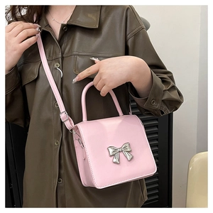 Detail of light pink mini square crossbody bag featuring a silver metal bow buckle