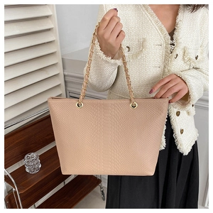 Detail of pink faux snakeskin tote bag featuring large capacity and gold chain straps