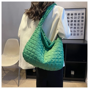 Detailed view of the green quilted puffer tote bag on a model in a minimalist room