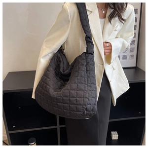 Detailed view of black quilted puffer tote bag with diamond stitching and soft padded strap