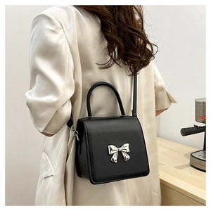 Classic black crossbody bag with silver bow buckle worn by model from a side view