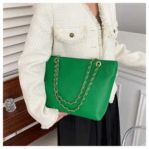 Close-up of bright green tote bag featuring crocodile embossed texture and gold chain strap