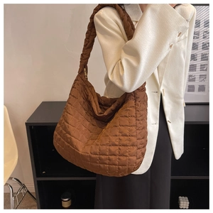 Detailed side view of brown quilted nylon tote bag with golden zipper and padded texture