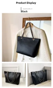 Detail of black crocodile texture tote bag with gold chain strap on white outfit