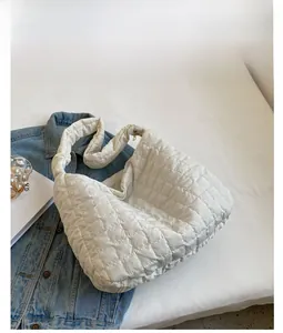 Close-up of white quilted cloud bag featuring soft padded nylon and gold zipper detail