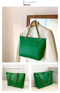 Close-up of green crocodile-embossed tote bag with gold metal chain strap and luxury texture