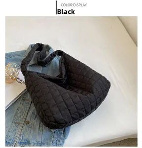 Detail of black quilted tote bag showing padded grid texture and soft nylon shoulder strap