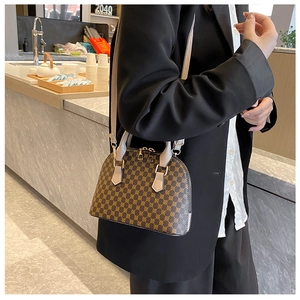 Detail of vintage shell bag with brown monogram pattern on model in black blazer