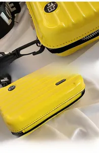 Detail of yellow mini suitcase bag showing the durable metal hook and wear-resistant base